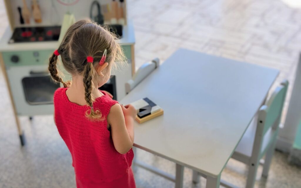 Bambina che gioca con materiale apposito per migliorare la coordinazione occhio mano e la motricità fine.